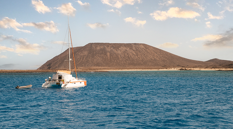 Catamarano ormeggiato con le vele riposte e il sole che si riflette sull'acqua